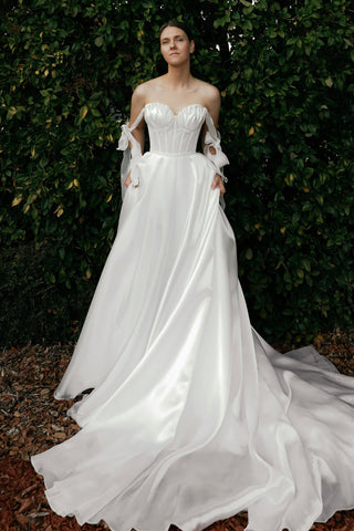 Woman in a white wedding dress standing in front of green foliage